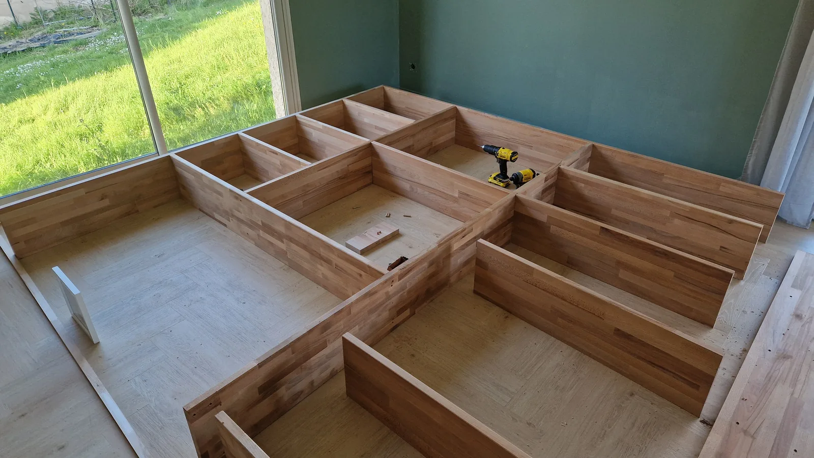 Assembled wooden bookshelf carcass on the floor of the green room, fitting the exact footprint the 3D scan predicted