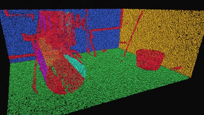 A room broken into individual objects, a red table and a red bin standing on a green floor against a blue wall and a yellow wall.